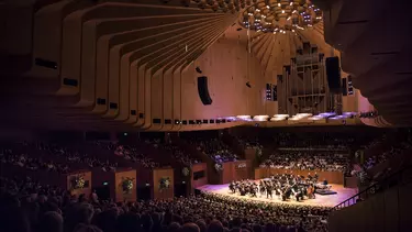 An orchestra performing on stage in the Concert Hall as viewed from the back of the Hall.