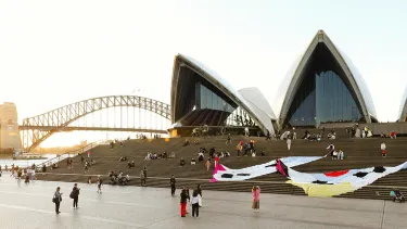 The sun sets over the Opera House as large tapestries drape on the forecourt steps.