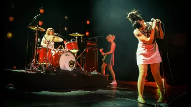 Bikini Kill a rock band performing on the stage.