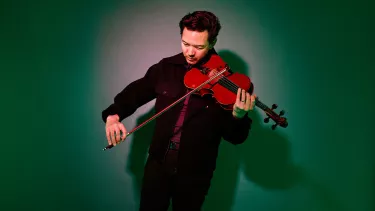 A man in black jacket playing a violin.