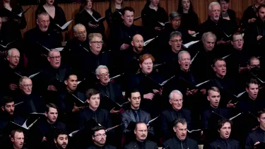 A choir singing with black folders in their hands.