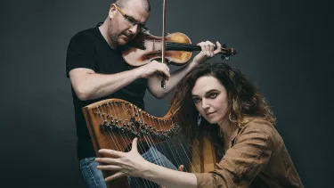 A man playing a violin and a woman playing a harp.