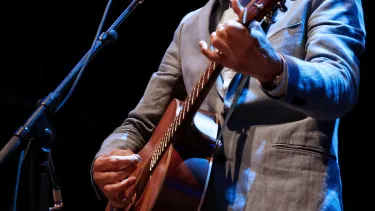 An Australian singer holding a guitar performing on the stage.