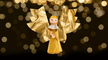 A golden doll of a Christmas Caroler with paper angel wings