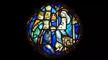 A medieval glass stained window of three kings bringing gifts to the Mother Mary and Jesus