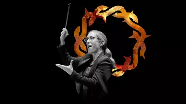 Woman conducts with a baton in her right hand and a graphic of a crown of thorns as the background