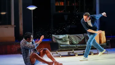 A man hurls water at another man in his nightgown on stage.