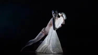 A dancer holds a cape of light.