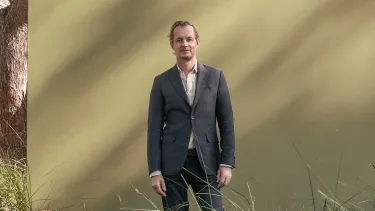 man stands in front of a khaki coloured screen in the AUstralian bush