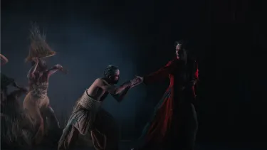 A dancer clasps the hands of a dancer dressed in red.