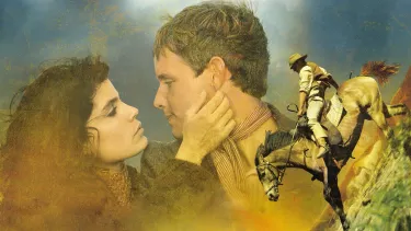 In the background, a woman with long brown hair looks loving at a man with her hand on his face. In foreground, a man wearing a cowboy hat and vest is riding a horse downhill.