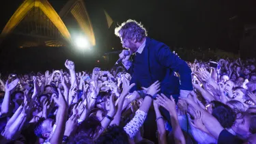 A man singing as the crowd lifts him up.