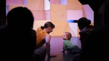 A woman and child look at each other happily at the front of a stage.