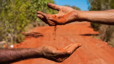 One hand dropping sand into another hand.