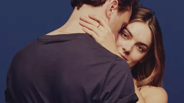 A man leaning this head on a woman's forehead and holding each other.