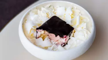 A black-pink dessert surround by white petals.