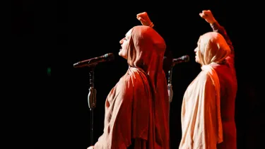 Two women wearing burkas raising their fist in the air.