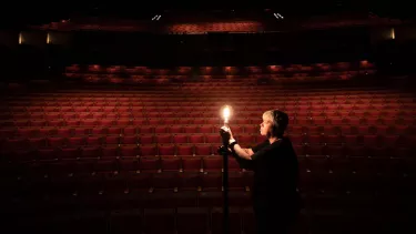 Person holding up a light in front of an empty theatre.