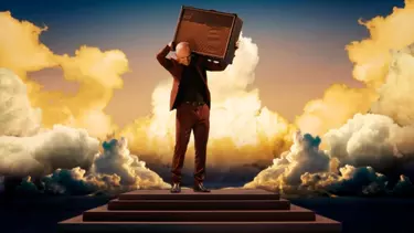 A man holding a speaker over his shoulder on steps with clouds surrounding.