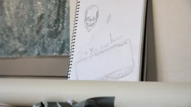 An open notebook with sketches of skulls in it.