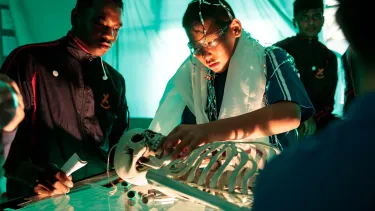 Two boys from Liverpool High stand over a lit up skeleton