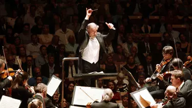 A conductor conducts the London Symphony Orchestra.