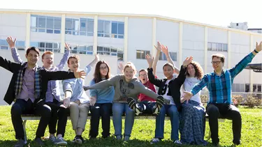 A group of men and women sitting on the bench with their arms wide open.