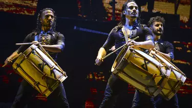 A group of men playing drums on a stage.