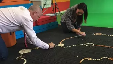 A man and a woman doing art with pebbles on the floor.