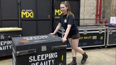 A girl pushes a box on wheels labelled Sleeping Beauty.