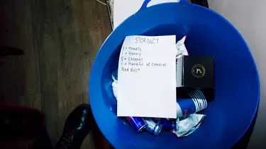 A bucket with ice and drinks in, with a paper list.