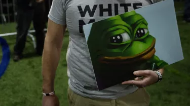 A person holding a poster with a frog on.