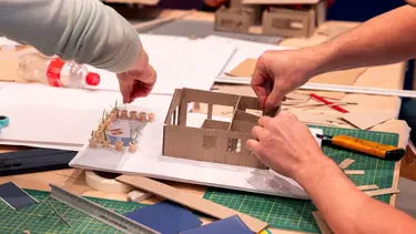 A child builds a house out of cardboard.