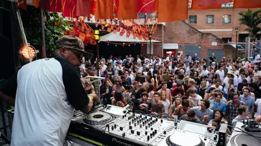 A DJ playing in front of a lively outside audience.