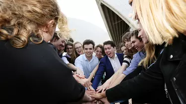 A group of people in a circle stacked their arms.