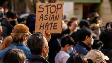 A crowd of people in masks with a sign titled 'Stop Asian Hate'.