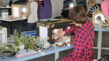 A young boy moving toy cars within a cardboard box