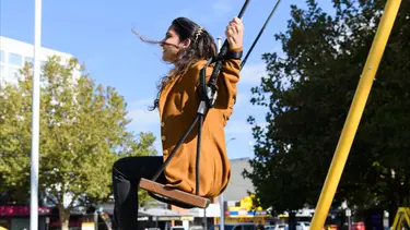 A lady on a giant yellow swing flying through the air.