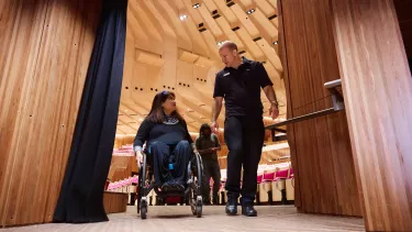 A man escorting a woman on a wheelchair.