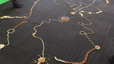 A man and a woman doing art with pebbles on the floor.