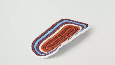 A small, colorful woven rounded mat.