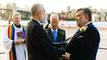 Two men getting married in suits.