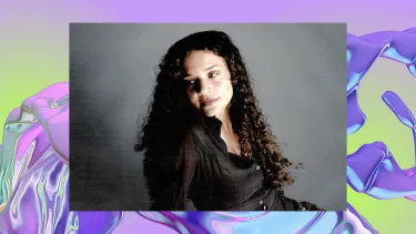 Portrait of a woman with long curly hair and a gentle smile against a grey backdrop. The image bac a background of a purple, iridescent swirl, looking like water.