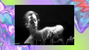 A black and white image shows a man DJing with audio equipment. The background is a purple, iridescent swirl, looking like water.