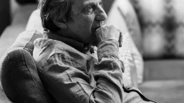 A man sat on a sofa looking into the distance.