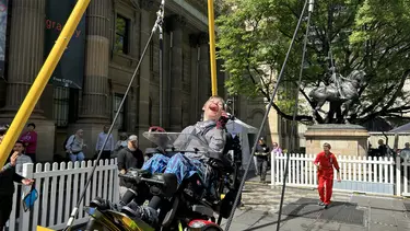 A person in a wheelchair rides the swing using a wheelchair attachment.