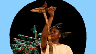 A woman stands on stage, holding a giraffe puppet.