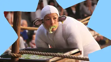 A performer dressed in a sheep costume is eating lettuce from a trough.