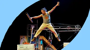A man leaps off a washing machine with his arms out wide.