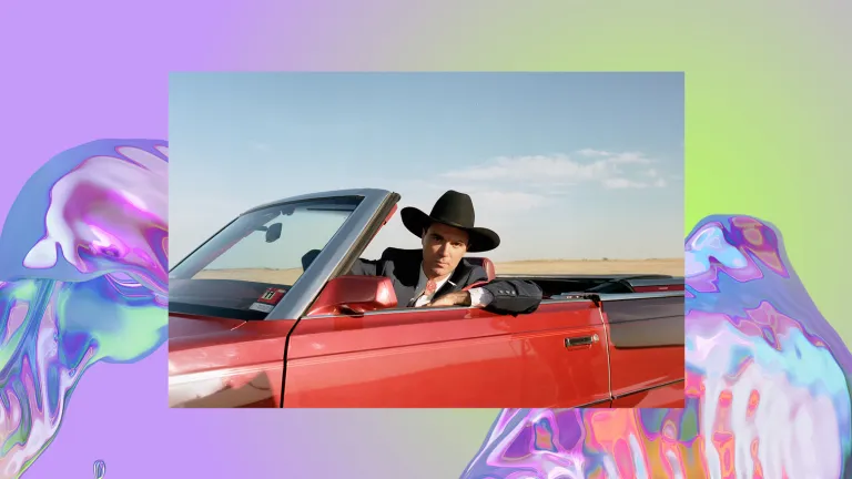 A man wearing a cowboy hat and suit sits in a red convertible.